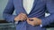 A man buttoning his jacket, close-up. Successful young man puts on a suit jacket