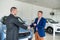 man buys an expensive car representative of car dealership shakes his hand as sign of agreement