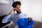 Man Calling Plumber While Leakage Water Falling Into Bucket