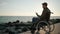 Man is calling by video in smartphone sitting in wheelchair on sea coast