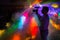 A man with a camera shoots a video at a disco with neon rays