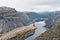 Man with camera sitting on Trolltunga rock Troll`s Tongue rock