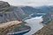 Man with camera sitting on Trolltunga rock Troll`s Tongue rock