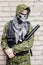 A man in camouflage, balaclava with a skull and bulletproof vest, with a baseball bat in his hands