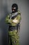 A man in camouflage and bullet proof vest, with a balaclava on his head.  A special unit soldier, a modern warrior.