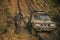 Man in camouflage clothing stands near suv covered with dirt