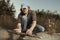 Man camping in nature making fire with wood stick friction by hands