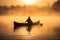 A man in canoe on a foggy tranquil lake with forest at sunrise. Winter Autumn seasonal concept.