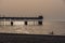 Man canoeing on the sea and Pier silhouettes at golden hour.