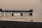 Man canoeing on the sea and Pier silhouettes at golden hour.