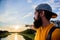 Man in cap enjoy sunset while stand on bridge. Take moment to admire sunset nature beauty. River sun reflection. Enjoy