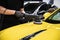 Man car detailing studio worker polishing yellow car varnish with electrical polisher