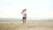 A man carries a child on his shoulder along a sandy beach near the sea shore, in slow motion