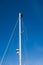 A man carries out work on the top of the mast of a sailboat