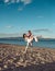 Man carries woman in white dress, couple happy on vacation. Couple in love stand on beach, seashore. Couple in love
