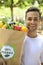 Man carrying recycle paper bag full of organic vegetable and fruits.