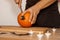 A man carves eyes and a mouth in a pumpkin for Halloween.