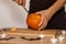 A man carves eyes and a mouth in a pumpkin for Halloween.