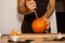 A man carves eyes and a mouth in a pumpkin for Halloween.