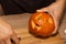 A man carves eyes and a mouth in a pumpkin for Halloween.