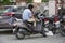 A Man casually sitting on his motorcycle and looking at phone outside a building. : Udaipur India - August 2020