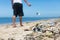 A man casually throws garbage on the ground, adding to the large amount of litter at the beach