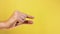 Man caucasian hand showing gesture of little size with two fingers, isolated over yellow background. Showing small thing gesture