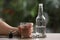 Man chained to glass of vodka at table against blurred background, closeup. Alcohol addiction