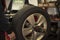 Man changing car tires in garage winter season. Workplace environment in dark colors, fitting the tire on rim, spinning tire.