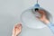 Man changing light bulb in pendant lamp on white background