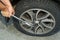 Man changing wheel. tire changer changing flat car tire. Help on road concept. Mechanic hands unscrews a flat tire of a car raised