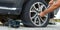 Man changing wheel. tire changer changing flat car tire. Help on road concept. Mechanic hands unscrews a flat tire of a car raised