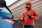 Man charging electric car during cold snowy day, using electric vehicle charging app, checking battery life, energy