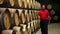 the man checking the barrels in the wine cellar