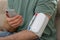 Man checking blood pressure with modern monitor and smartphone indoors, closeup