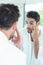 Man checking eyes in bathroom mirror