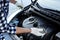 Man checking motor oil level with dipstick in car outdoors, closeup