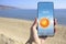 Man checking weather using app on smartphone on beach, closeup. Data and illustration of sun on screen