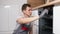 Man checks broken oven to repair siting on floor in kitchen