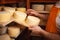 man cheesemaker in the cellar, beautiful wooden shelves with a