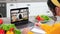 Man chef in laptop screen greets tells teaches housewife remote cooking lesson