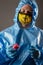 Man in chemical protection suit and mask with a virus in hands in studio shot