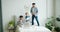 Man and child jumping on bed while girl mother using smartphone