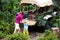 Man and child push car stuck in mud in jungle. Family pushing off road vehicle stuck in muddy dirt terrain in tropical forest.