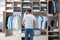 Man choosing outfit from large wardrobe closet with clothes, shoes and home stuff