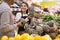 Man choosing ripe pineapples in supermarket and female store employee helping him