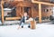 Man chopping wood on snowy yard for a house fireplace with heavy snowflakes background . Winter countryside holidays concept image