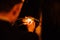 A man with a cigarette lighter sets fires on sparklers at night