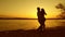 Man circling in happy girl dance. girl in love and man dancing on beach in evening in rays of a yellow sunset.