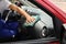 Man cleaning automobile dashboard with duster in vehicle.